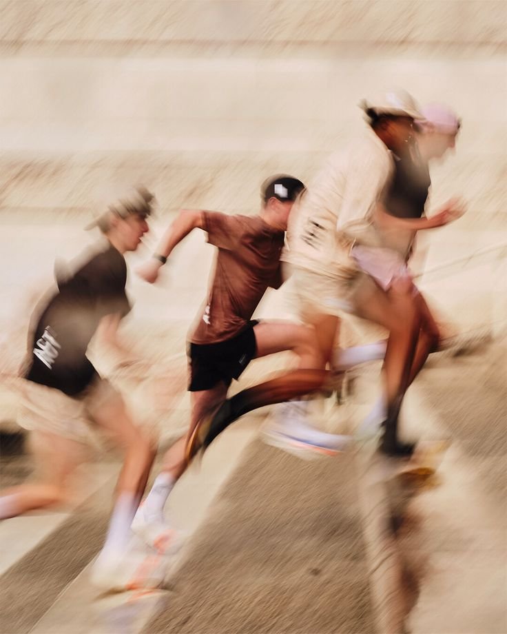 Four runners, captured in motion blur, running up a wide flight of stone steps outdoors.