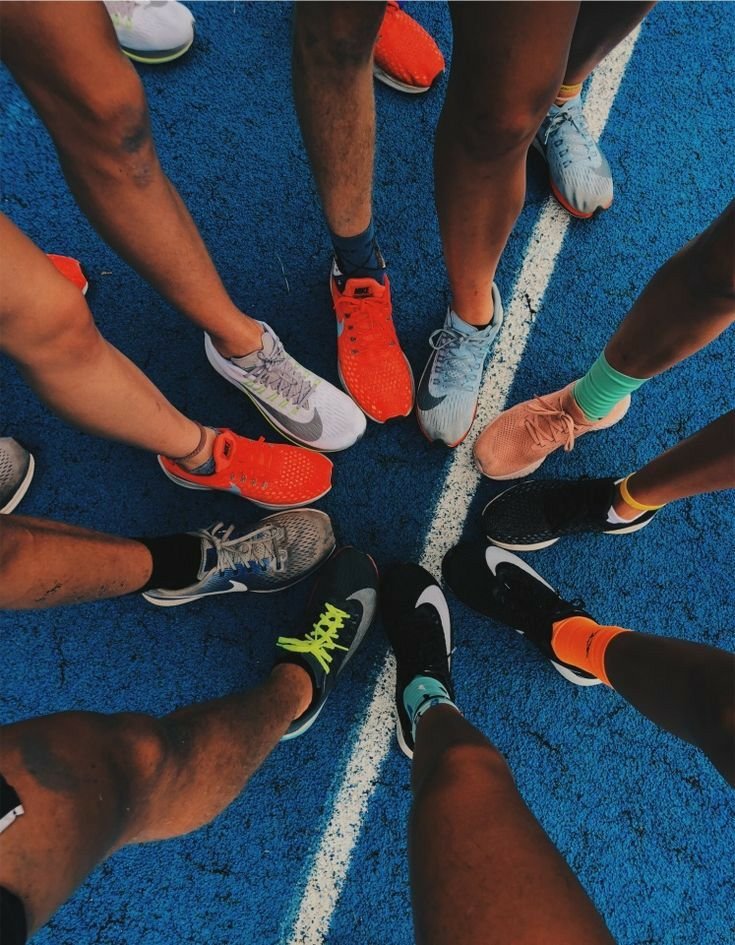 Overhead view of a group of runners standing in a circle on a blue running track
